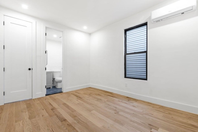 interior space featuring light hardwood / wood-style floors, a wall unit AC, and connected bathroom