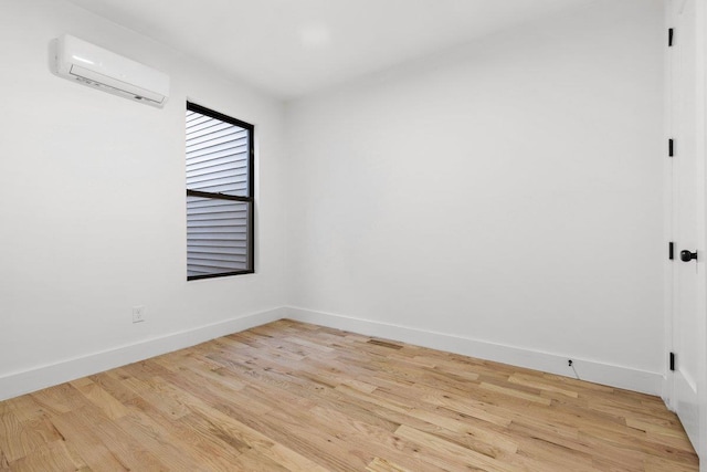 empty room featuring an AC wall unit and light hardwood / wood-style floors