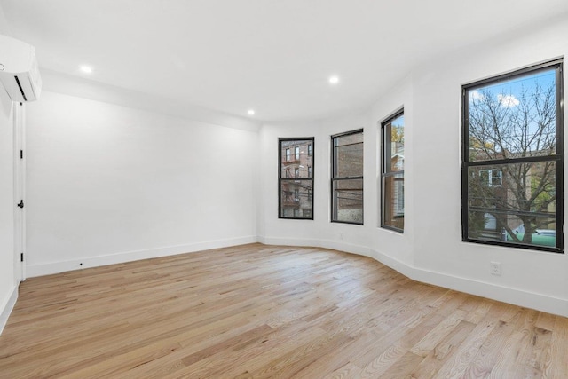 spare room with light hardwood / wood-style floors and an AC wall unit