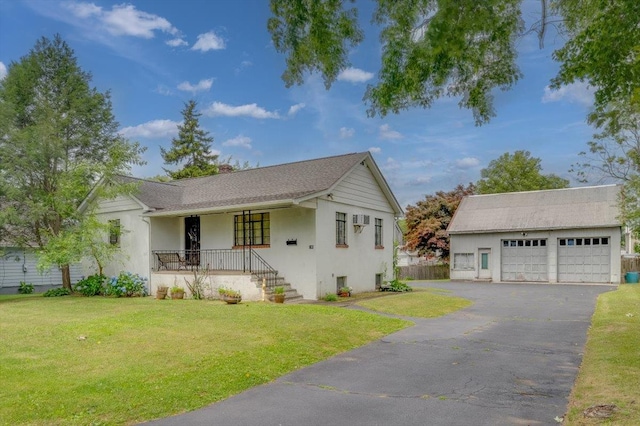 view of front of home with a garage, a front yard, a wall mounted AC, covered porch, and an outdoor structure