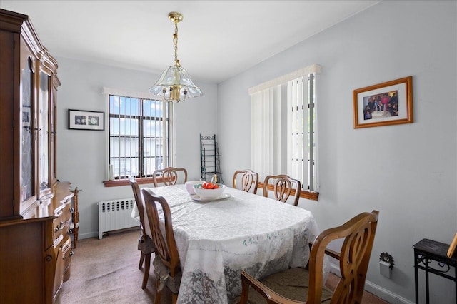 dining area with radiator heating unit, light colored carpet, and a notable chandelier