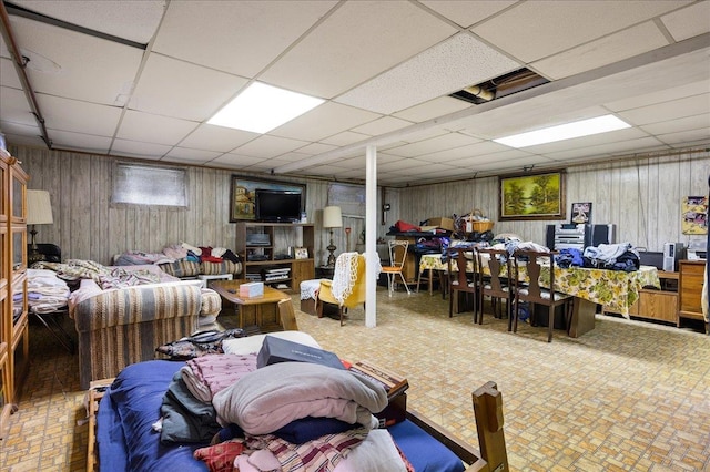 basement with a paneled ceiling and wood walls