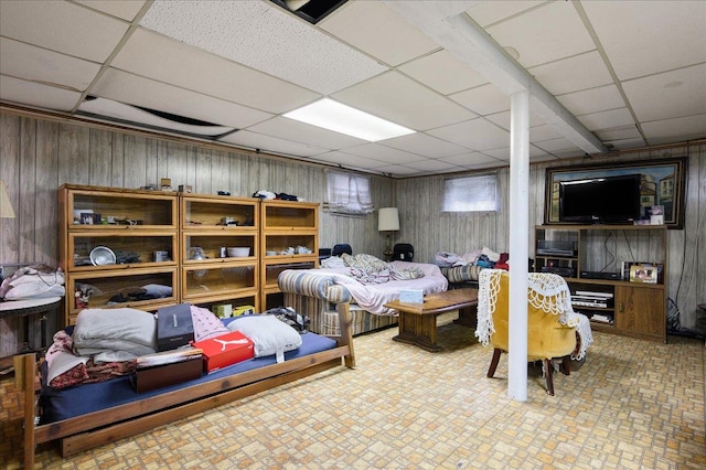 bedroom featuring a drop ceiling and wood walls