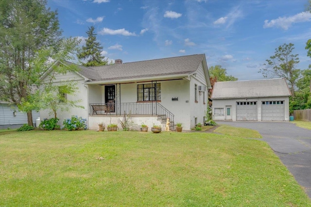 view of front of property with a front yard, a porch, a garage, and an outdoor structure