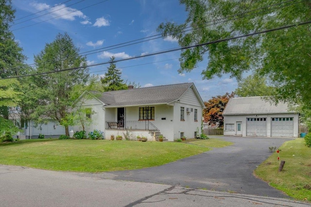 view of front of house featuring covered porch, a garage, a front lawn, and an outdoor structure