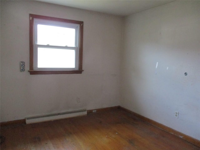 unfurnished room featuring baseboard heating and hardwood / wood-style flooring