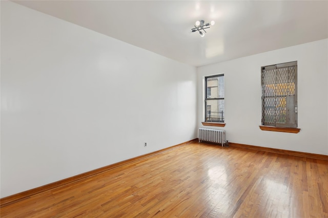 unfurnished room featuring a chandelier, radiator heating unit, and light hardwood / wood-style floors