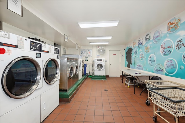 clothes washing area featuring dark tile patterned flooring and washer and clothes dryer