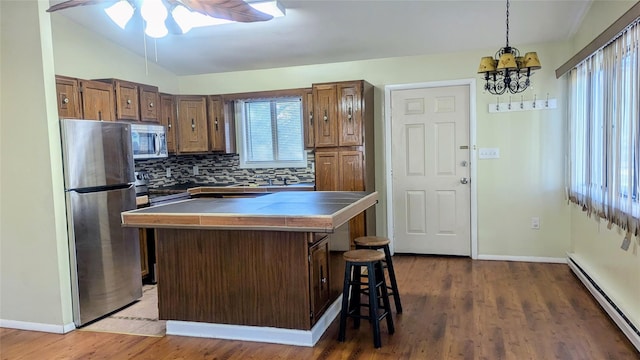 kitchen with a center island, a breakfast bar area, decorative backsplash, a baseboard radiator, and stainless steel appliances