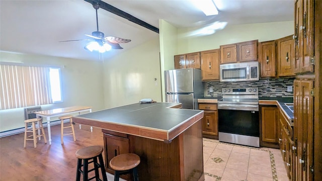 kitchen featuring a kitchen breakfast bar, vaulted ceiling with beams, tasteful backsplash, and stainless steel appliances