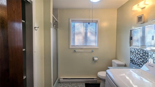 bathroom featuring vanity, a baseboard heating unit, toilet, walk in shower, and washer / clothes dryer