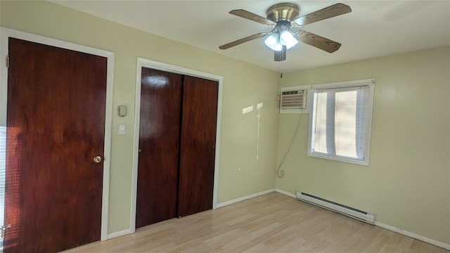 unfurnished bedroom featuring a wall unit AC, ceiling fan, a baseboard radiator, and light wood-type flooring