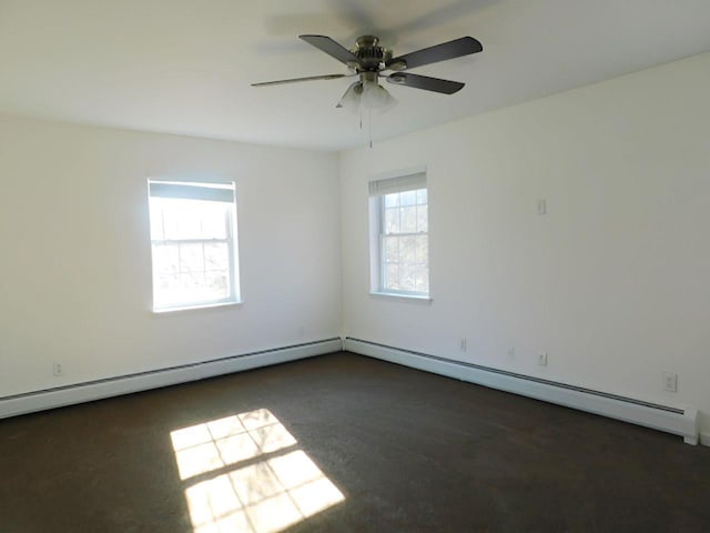 carpeted spare room with baseboard heating, a wealth of natural light, and ceiling fan