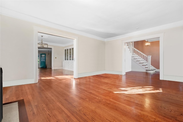 unfurnished room with wood-type flooring, crown molding, and a chandelier