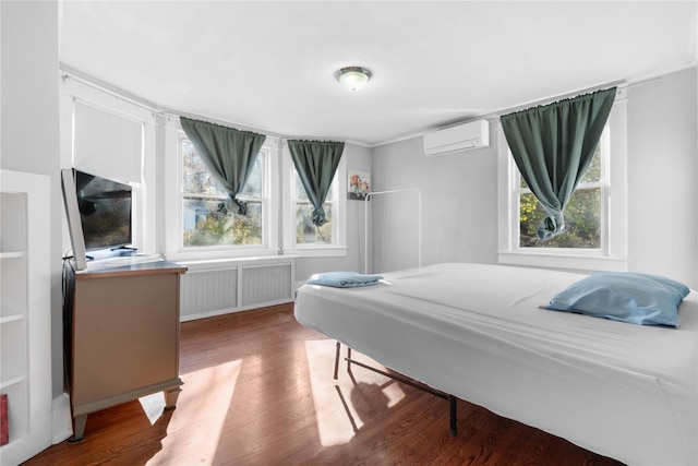 bedroom with radiator, a wall mounted air conditioner, and hardwood / wood-style flooring