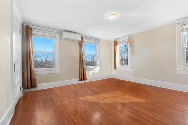 spare room featuring a wall mounted air conditioner and wood-type flooring