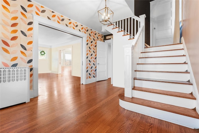 stairway featuring a chandelier, radiator heating unit, and hardwood / wood-style floors