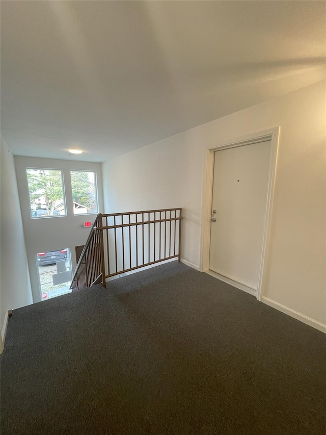 unfurnished room featuring dark carpet