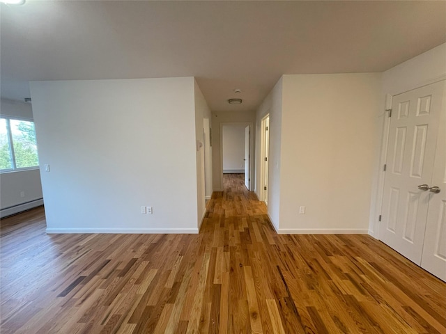 empty room with baseboard heating and light hardwood / wood-style flooring