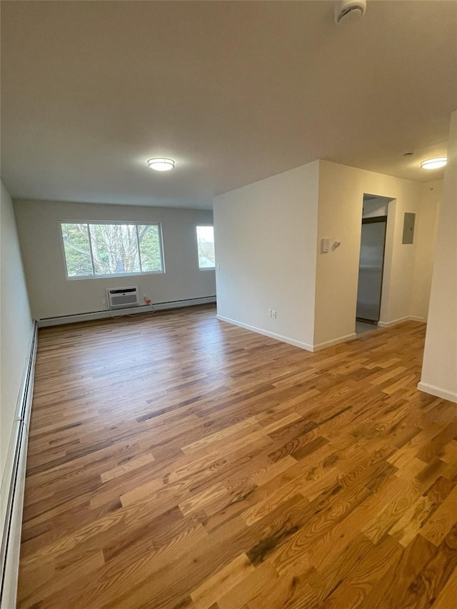 unfurnished room with a wall mounted AC, light hardwood / wood-style floors, and a baseboard heating unit