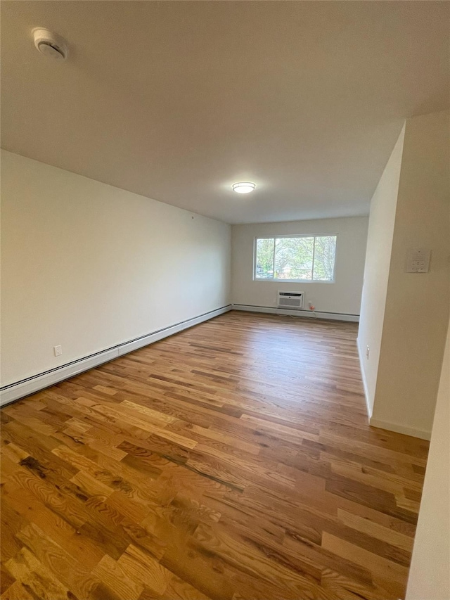 spare room with light hardwood / wood-style floors, a wall mounted air conditioner, and a baseboard heating unit