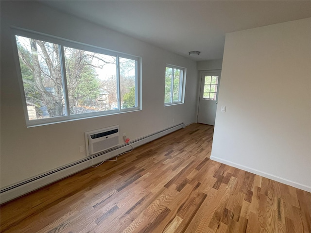 spare room featuring baseboard heating, a wealth of natural light, and light hardwood / wood-style floors