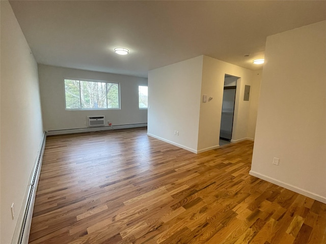 empty room with an AC wall unit, hardwood / wood-style floors, and a baseboard heating unit