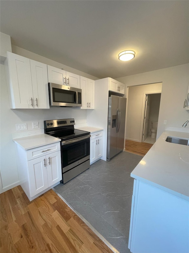 kitchen with white cabinets, hardwood / wood-style flooring, sink, and appliances with stainless steel finishes