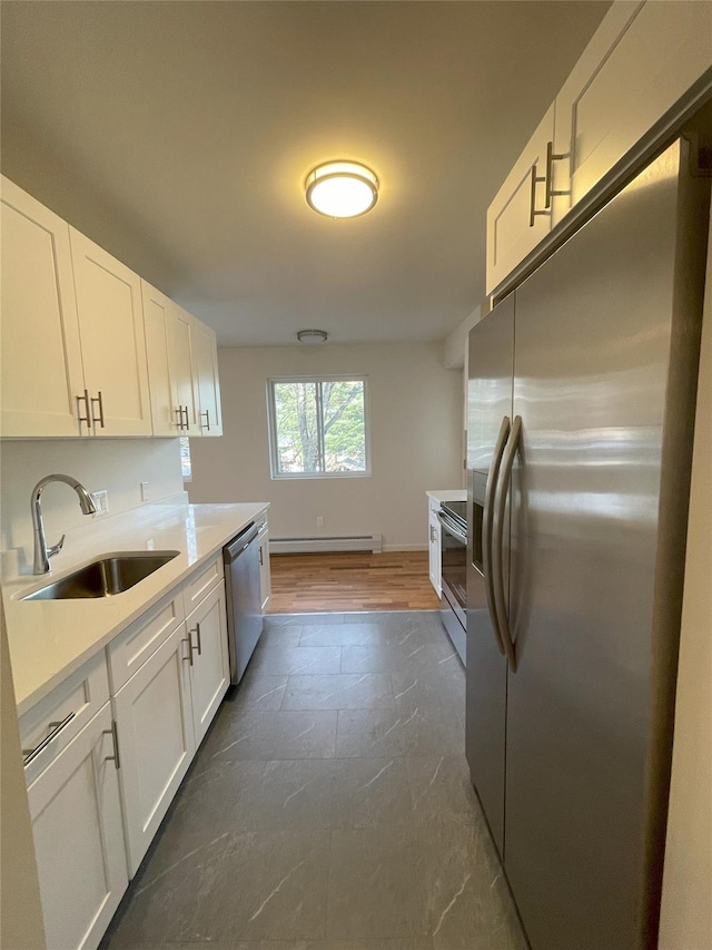 kitchen with dark hardwood / wood-style flooring, stainless steel appliances, a baseboard heating unit, sink, and white cabinets