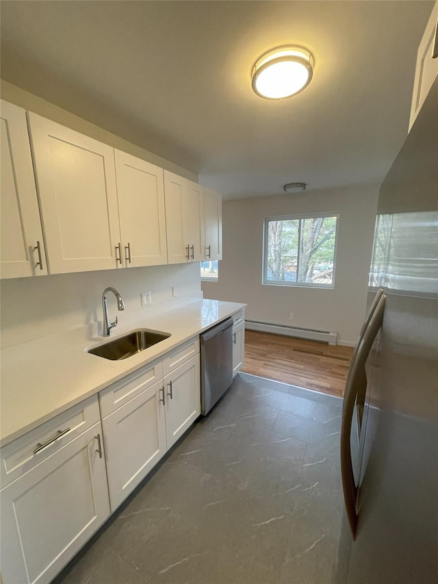 kitchen with a baseboard heating unit, white cabinetry, sink, and stainless steel appliances