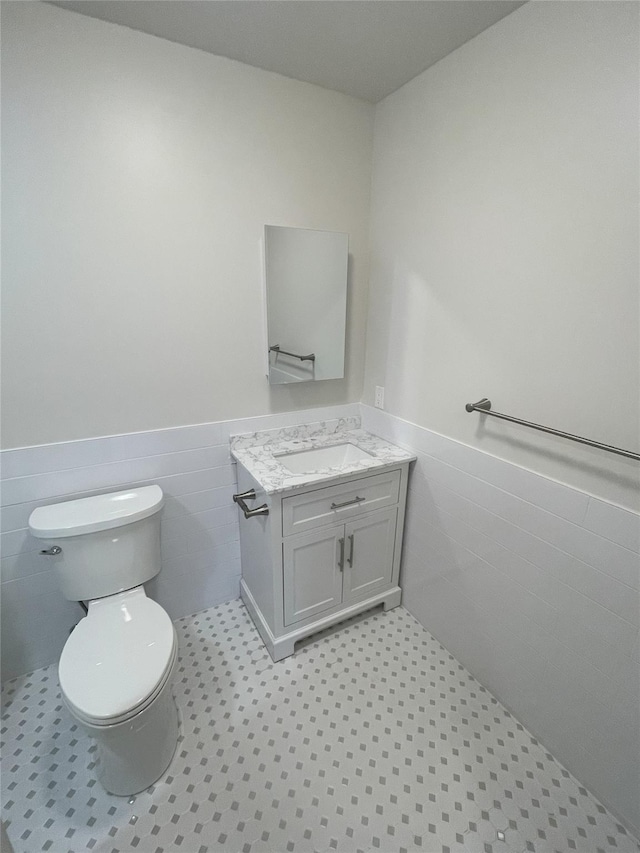 bathroom featuring tile patterned floors, vanity, tile walls, and toilet