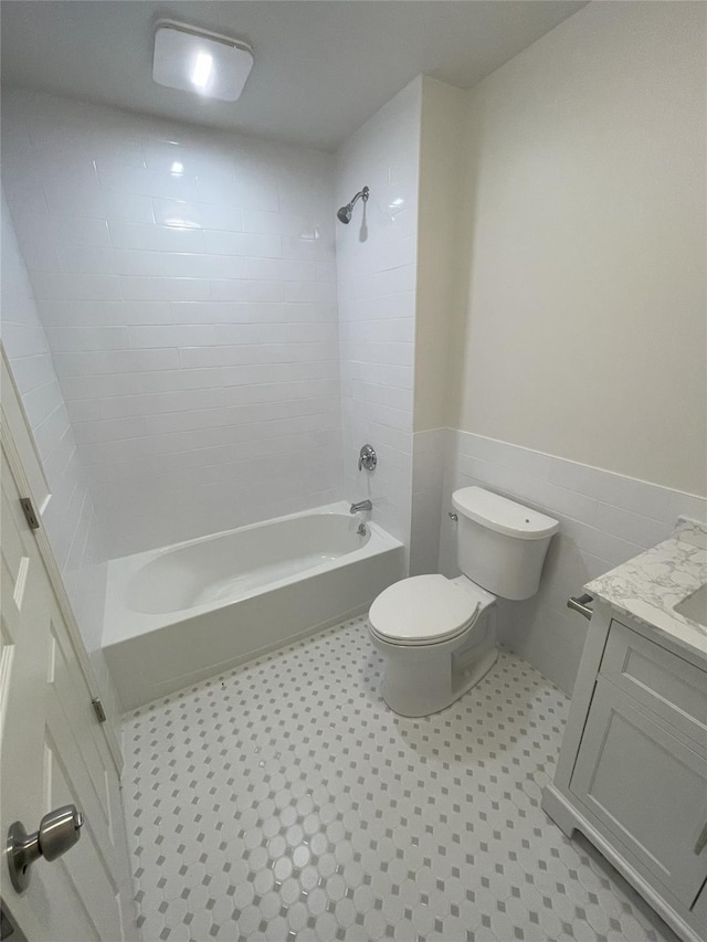 full bathroom featuring vanity, tiled shower / bath combo, tile walls, tile patterned flooring, and toilet