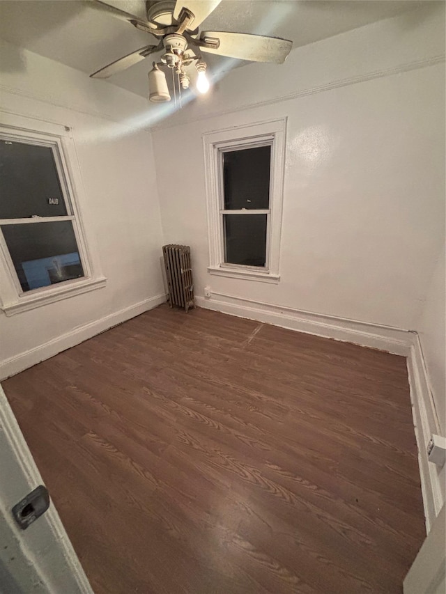 empty room featuring radiator, dark hardwood / wood-style floors, and ceiling fan