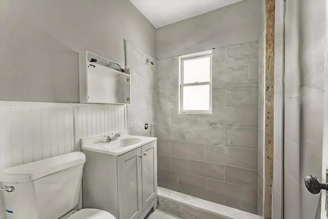 bathroom featuring vanity, toilet, and a tile shower