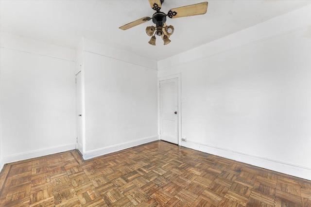 spare room with ceiling fan and dark parquet flooring