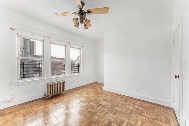 empty room with light parquet floors, radiator heating unit, and ceiling fan