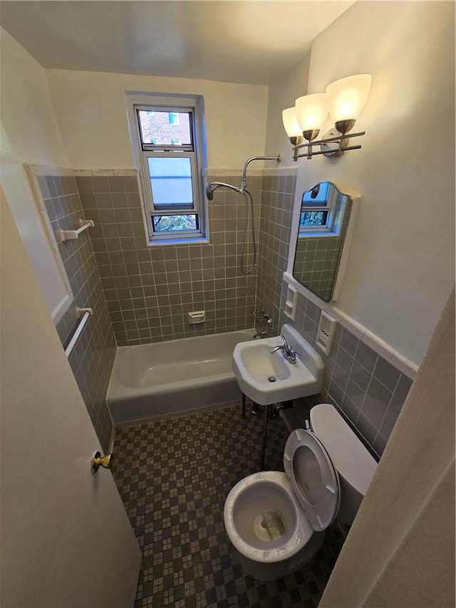 bathroom with a tile shower, tile walls, and toilet