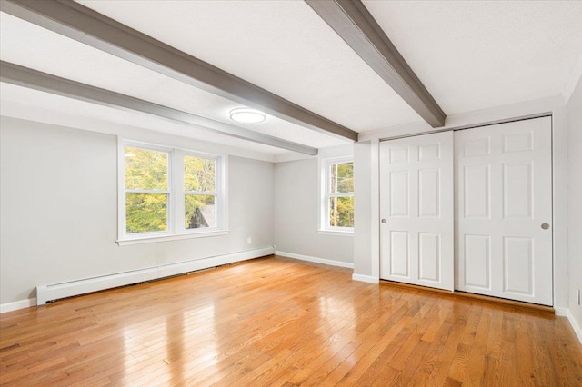 unfurnished bedroom featuring beam ceiling, a closet, a baseboard radiator, and light hardwood / wood-style floors