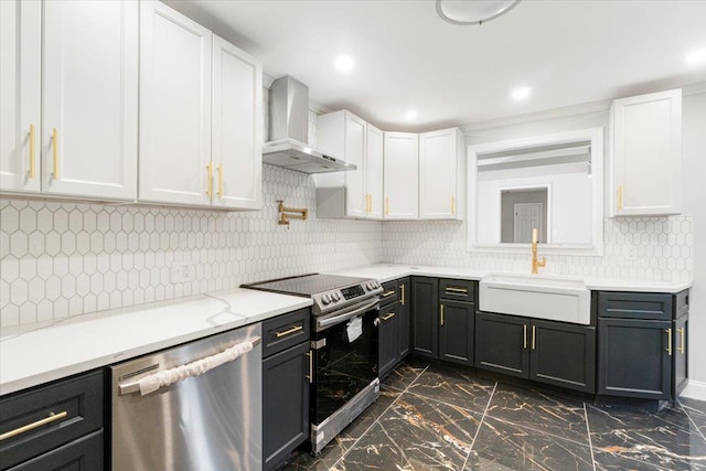 kitchen with white cabinets, wall chimney range hood, backsplash, and appliances with stainless steel finishes