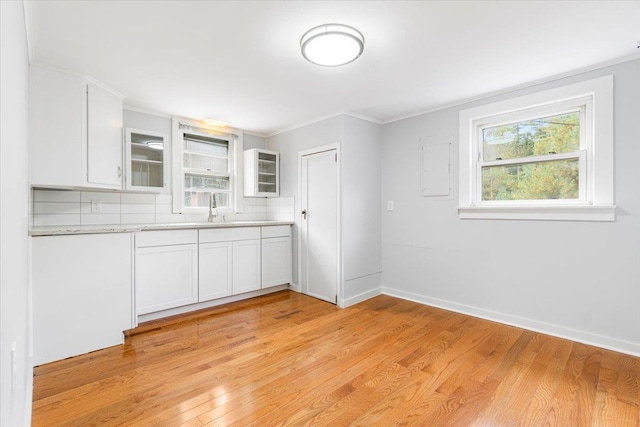 kitchen featuring white cabinetry, sink, crown molding, decorative backsplash, and light wood-type flooring