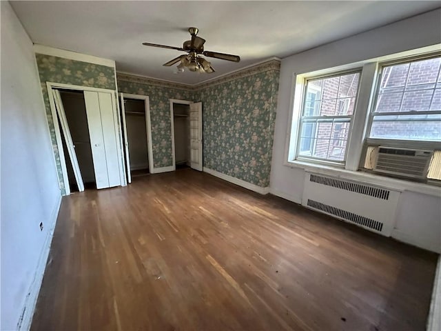 17506 Devonshire Blvd Unit 4C, Jamaica Hills, NY 11432 - unfurnished bedroom featuring radiator, wood finished floors, wallpapered walls, baseboards, and multiple closets