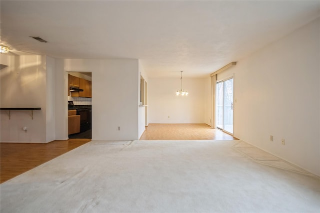 spare room featuring an inviting chandelier and light hardwood / wood-style flooring