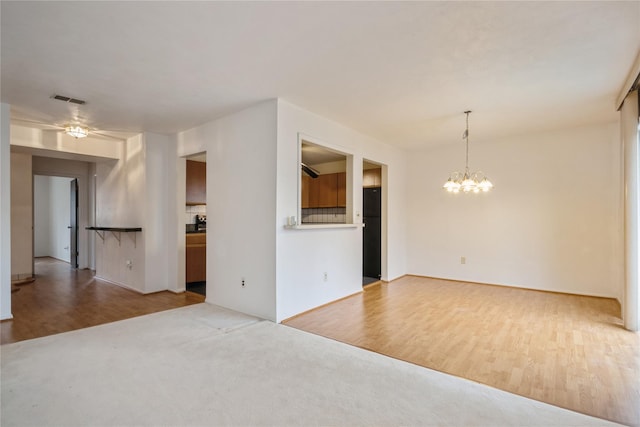 spare room with hardwood / wood-style flooring and ceiling fan with notable chandelier