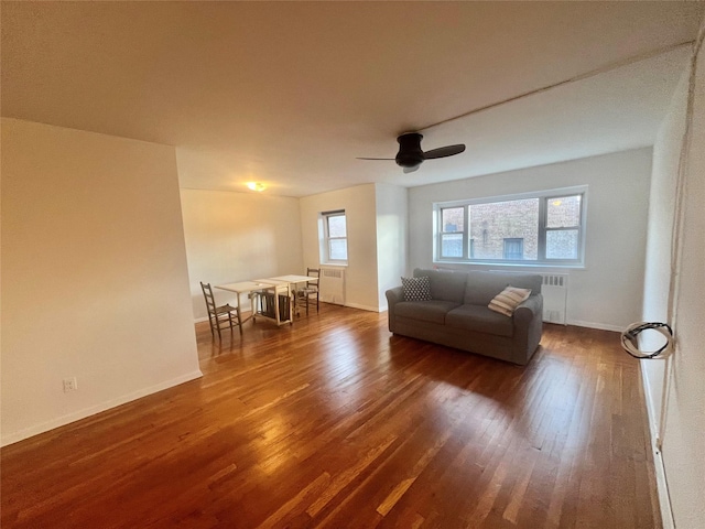 unfurnished living room with radiator heating unit, dark hardwood / wood-style flooring, and ceiling fan