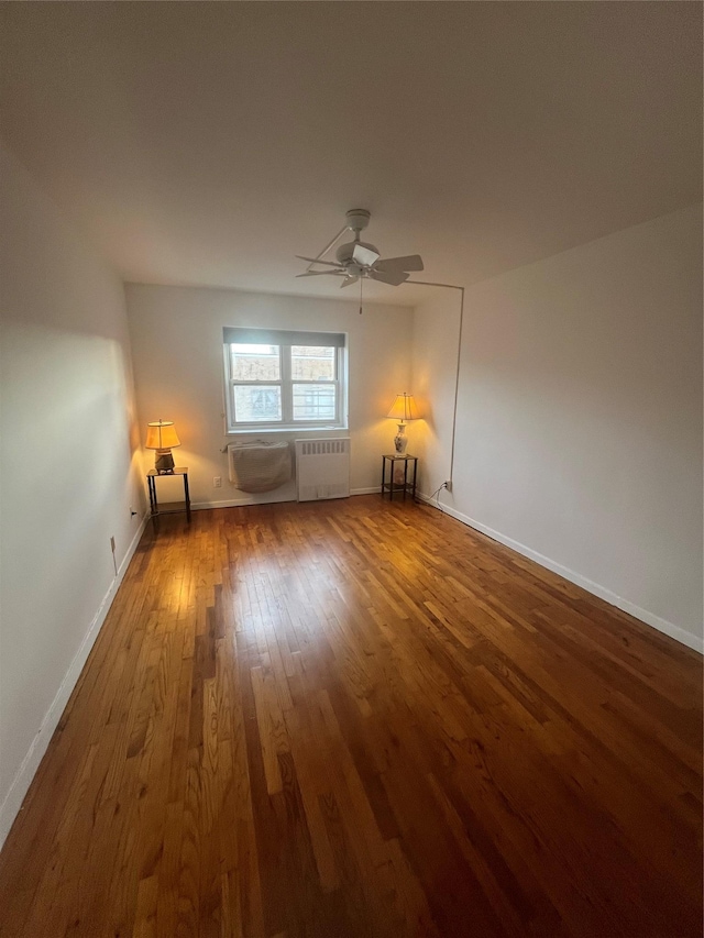 empty room featuring hardwood / wood-style flooring, ceiling fan, and radiator heating unit