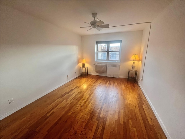 empty room with ceiling fan, radiator heating unit, and wood-type flooring