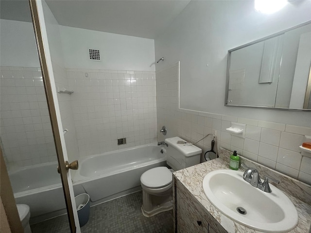 full bathroom with toilet, tiled shower / bath, and tile walls