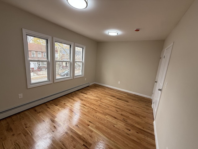 empty room with light hardwood / wood-style floors and baseboard heating