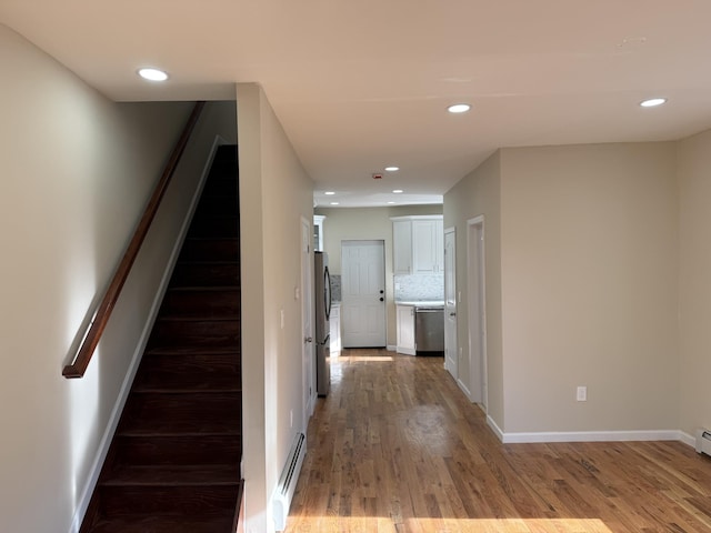 stairway with hardwood / wood-style floors and a baseboard heating unit