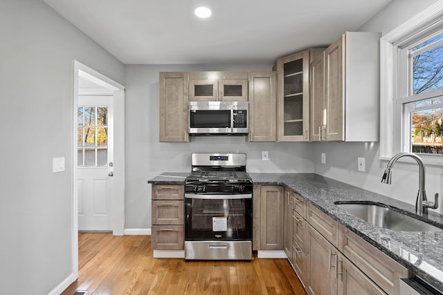 kitchen featuring light brown cabinets, dark stone counters, sink, light hardwood / wood-style floors, and stainless steel appliances